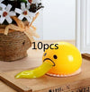 Funny vomiting egg yolk toy on table, stress relief squishy prank gift, 10 pieces, with decorative flowers in the background.