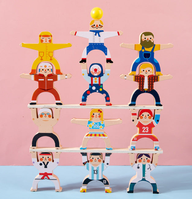 Colorful wooden toy figures stacked in rows, balancing and creating a fun, playful tower against a pink background.