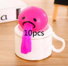 Pink squishy toy with vomiting design placed on a white cup, perfect for stress relief and prank gifts.