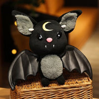 Plush black bat toy with a crescent moon, featuring soft fabric and cute details, perfect for cuddling or decoration.