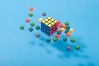 Colorful cube puzzle surrounded by scattered blocks on a blue background.