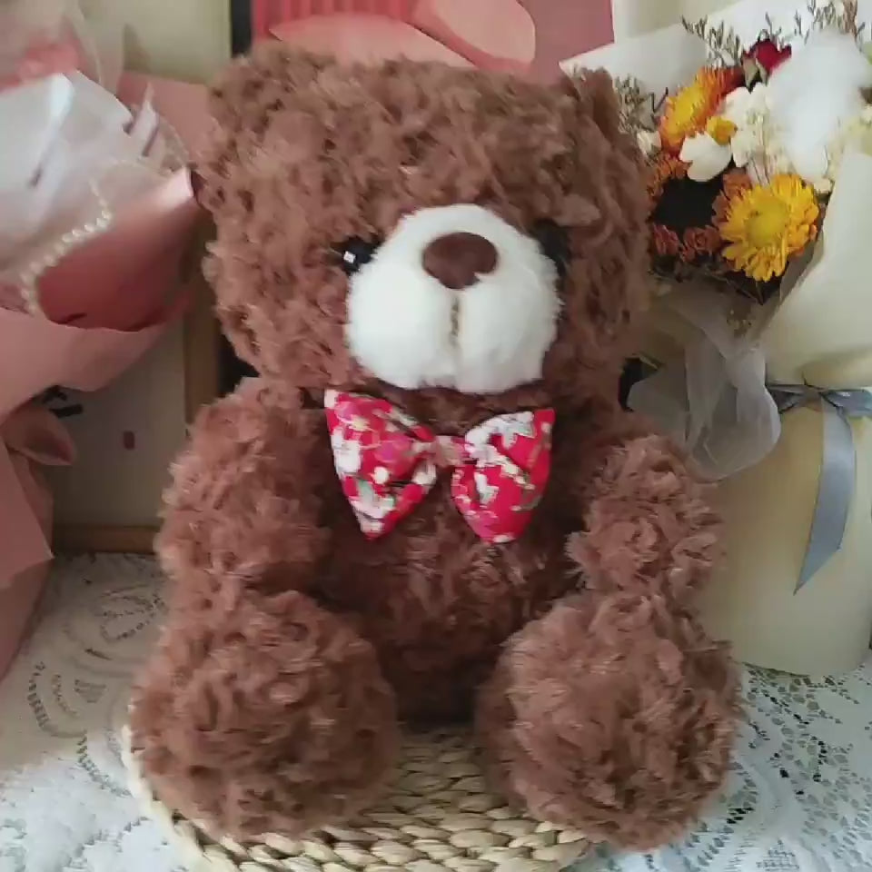 dark brown teddy bear sitting on bed