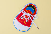 Colorful shoe-shaped paper with laces on a yellow background, ideal for teaching kids how to tie shoelaces.