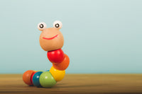 Colorful wooden caterpillar toy with a smiling face on a wooden surface against a blue background.